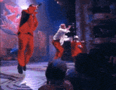 a man in a red suit is singing into a microphone in front of a crowd