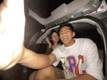 a man wearing a shirt that says rc is sitting in the back of a car with a woman