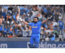 a cricket player is holding his bat and helmet in the air while playing a game of cricket .
