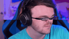 a man with glasses and headphones is sitting in a blue chair .