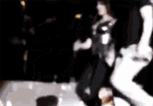 a blurry picture of a woman in a black and white outfit dancing in a dark room .