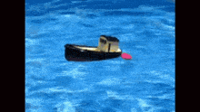 a toy boat is floating on top of a blue pool of water .