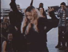 a woman with blonde hair is standing in front of a crowd
