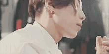 a close up of a man 's face wearing a white shirt and red earrings .