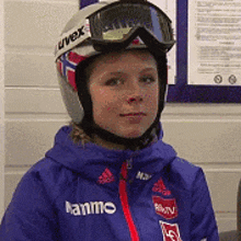a young girl wearing a helmet and goggles is wearing a blue jacket with the word hanne on it .