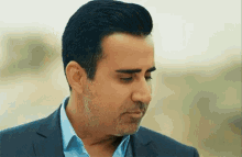 a man in a suit and a blue shirt is looking down .