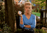 a woman in a blue shirt is holding a small container that says ' bbc ' on it