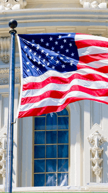 an american flag is waving in front of a white building
