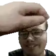 a man wearing glasses and a black shirt is smiling while a hand reaches for his forehead .