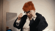 a woman with red hair and glasses is adjusting her jacket