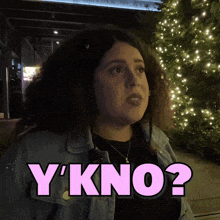 a woman with curly hair is standing in front of a christmas tree and says " y'kno "