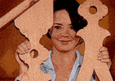 a woman is smiling while holding two wooden pieces