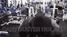 a man is lifting a barbell in a gym and the name gary buster holmes is on the bottom
