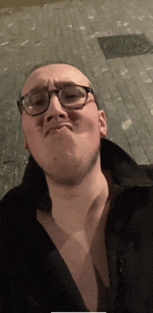 a man wearing glasses and a black shirt makes a funny face