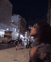 a woman wearing sunglasses is standing on a street at night