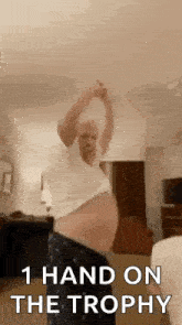 a man with a big belly is dancing in a living room while holding a trophy .