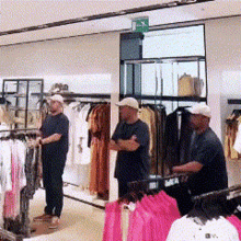 two men are standing in a clothing store with a green exit sign above them