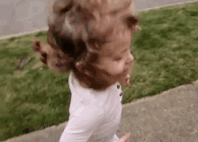 a little girl in a white shirt is running down a sidewalk .