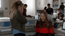 two women are standing next to each other in an office with #youngertv written on the bottom of the screen
