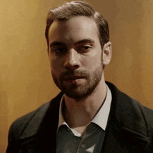 a man with a beard wearing a black coat and white shirt