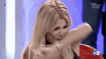 a woman with blonde hair is sitting in front of a screen that says el mundo de hermano