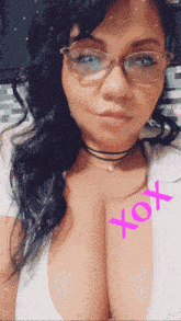 a woman wearing glasses and a choker has a pink xoxo written on her chest