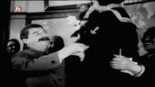 a man with a mustache is talking to a girl in a black and white photo with the letter h on the bottom