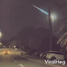 a shooting star is visible in the night sky above a street