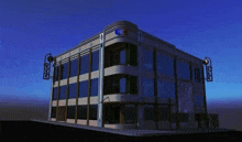 a large building with a lot of windows is sitting on the corner of a street at night .