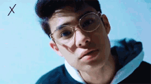 a close up of a young man wearing glasses and a hoodie