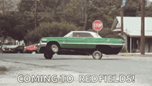 a green lowrider car is driving down a street with a stop sign in the background