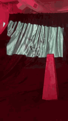 a green cloth is draped over a red cone in front of a black curtain