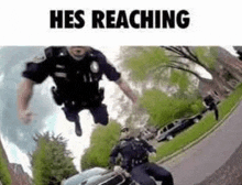 a police officer is jumping in the air while riding a motorcycle next to a car .