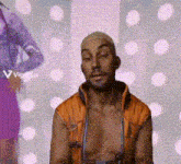 a man without a shirt is standing in front of a wall with polka dots .