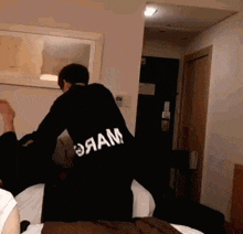 a person wearing a black shirt that says ' oaam ' on the back of it