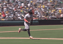 a baseball player wearing a giants jersey is running towards home plate
