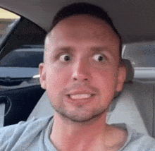 a man is sitting in the back seat of a car making a funny face