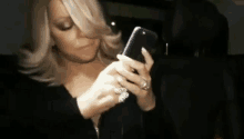 a woman is holding a cell phone in her hand while wearing a ring .
