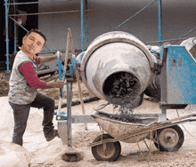 a man is pouring cement into a wheelbarrow while wearing a grey vest