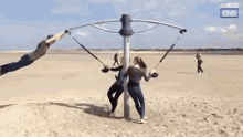 a group of people are playing on a swing set on a beach with collab clips written on the bottom