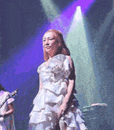 a woman in a white dress is singing into a microphone