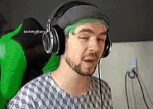 a man with green hair is wearing headphones while sitting in a chair .