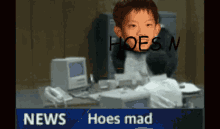a boy is sitting at a desk in front of a computer with the words hoes n written on his face