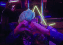 a man with blue hair is making a face in front of a neon light