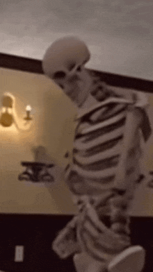 a skeleton is standing on a bed in a room holding a book .