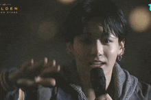 a close up of a person holding a microphone with the words lden on stage behind them