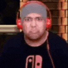 a man wearing headphones and a hat is making a funny face .