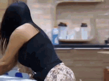 a woman in a black tank top and floral shorts is kneeling down