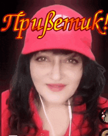 a woman wearing a red hat and ear buds is smiling in front of a sign that says tpybemuk