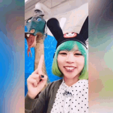 a woman with green hair and glasses is wearing bunny ears and a mickey mouse hat